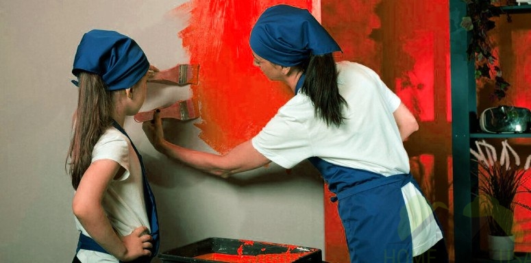 Two girls paint a wall in red